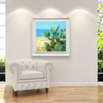 Modern oil painting on canvas of a beach with cacti hanging in a modern living room with a white sofa and home decor