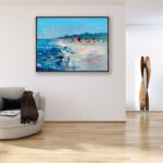 Beach oil painting on canvas with rich impasto texture hanging in a modern living room with a beige sofa, showing full room decor.