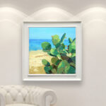 Modern oil painting on canvas of a beach with cacti hanging in a modern living room with a white sofa and home decor